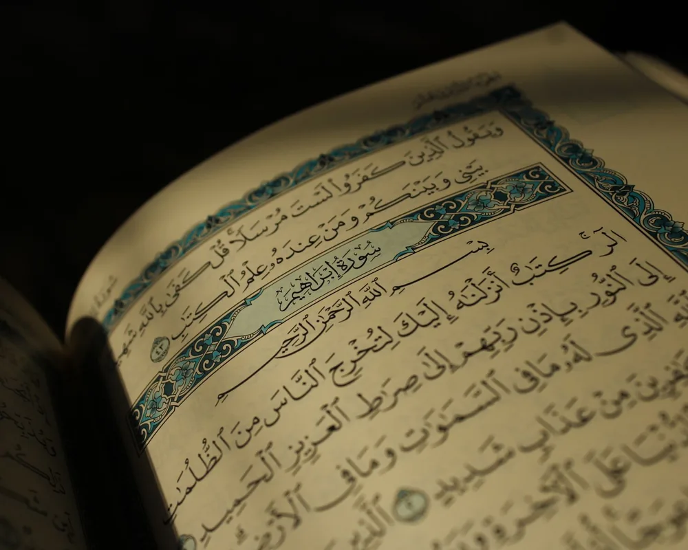 An open muṣḥaf showing illuminated Arabic pages in low light